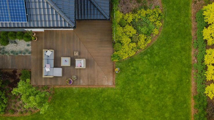 Ein Haus mit Terrasse und einer Photovoltaik auf dem Dach aus der Vogelperspektive.