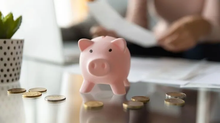 Ein Sparschwein mit Geldmünzen auf dem Tisch. Sie stehen für anstehende Kosten einer Fußbodenheizung.