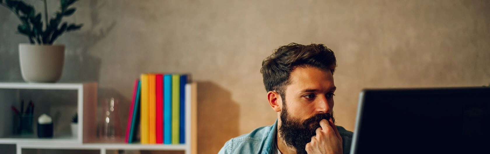 Ein Mann sitzt vor seinem Laptop und überlegt wie er seinen Problemmietern kündigen kann.