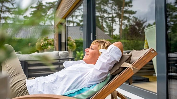 Eine Frau entspannt auf der Terrasse ihrer Ferienwohnung.