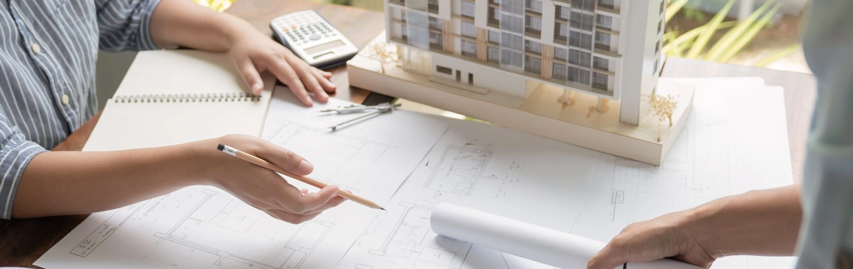 Ein Hausmodell und Baupläne deuten auf einen Immobilienumbau hin.