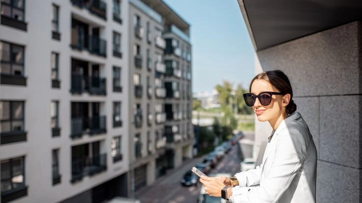 Eine Immobilienmaklerin wartet auf dem Balkon auf die nächsten Kundinnen und Kunden.