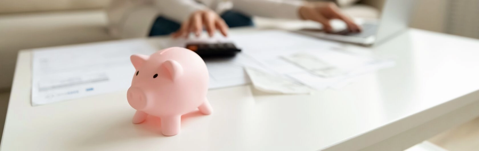 Eine Frau prüft Dokumente. Ein Sparschwein liegt auf dem Tisch. Das Bild symbolisiert den Kreditverkauf.