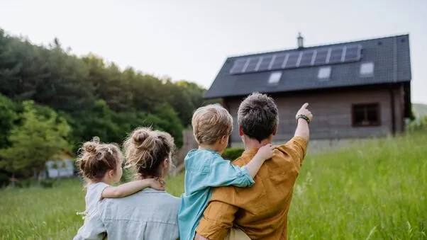 Symboldbild für das KfW-Programm 308: Eine Familie steht im Grünen und blickt auf ihr Haus.