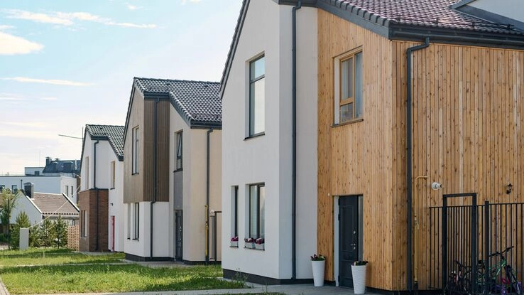 Moderne neue Reihenhäuser, die teils mit Holz verkleidet sind, sind zu sehen und stehen für den Hauskauf mit Hilfe eines KfW-Programmes.