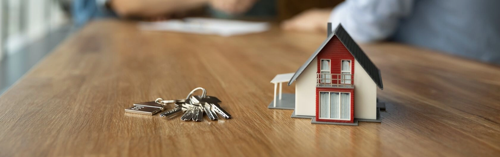 Ein kleines Haus und ein Schlüsselbund stehen für das Thema Immobilienkauf.