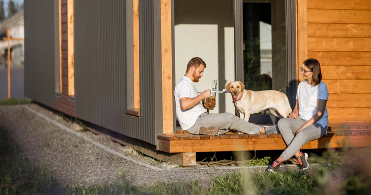 Symbolbild für alternative Wohnformen - Ein Pärchen vor ihrem Tiny House.
