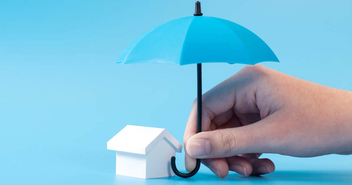 Ein Schirm wird über ein kleines Haus gespannt. Diese Darstellung symbolisiert die News zur Erbschaftssteuer.